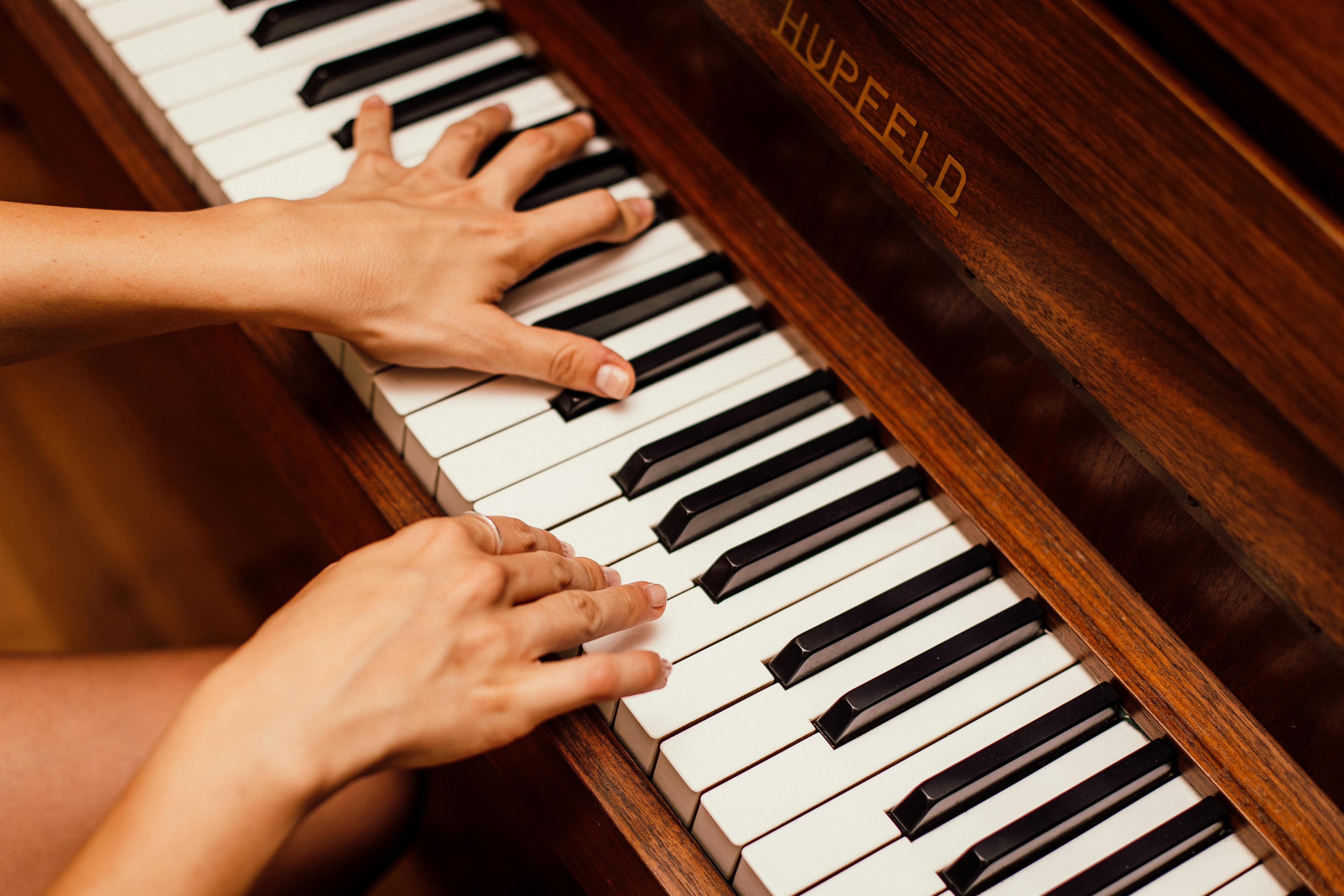 Duas mãos brancas e feminas tocando piano